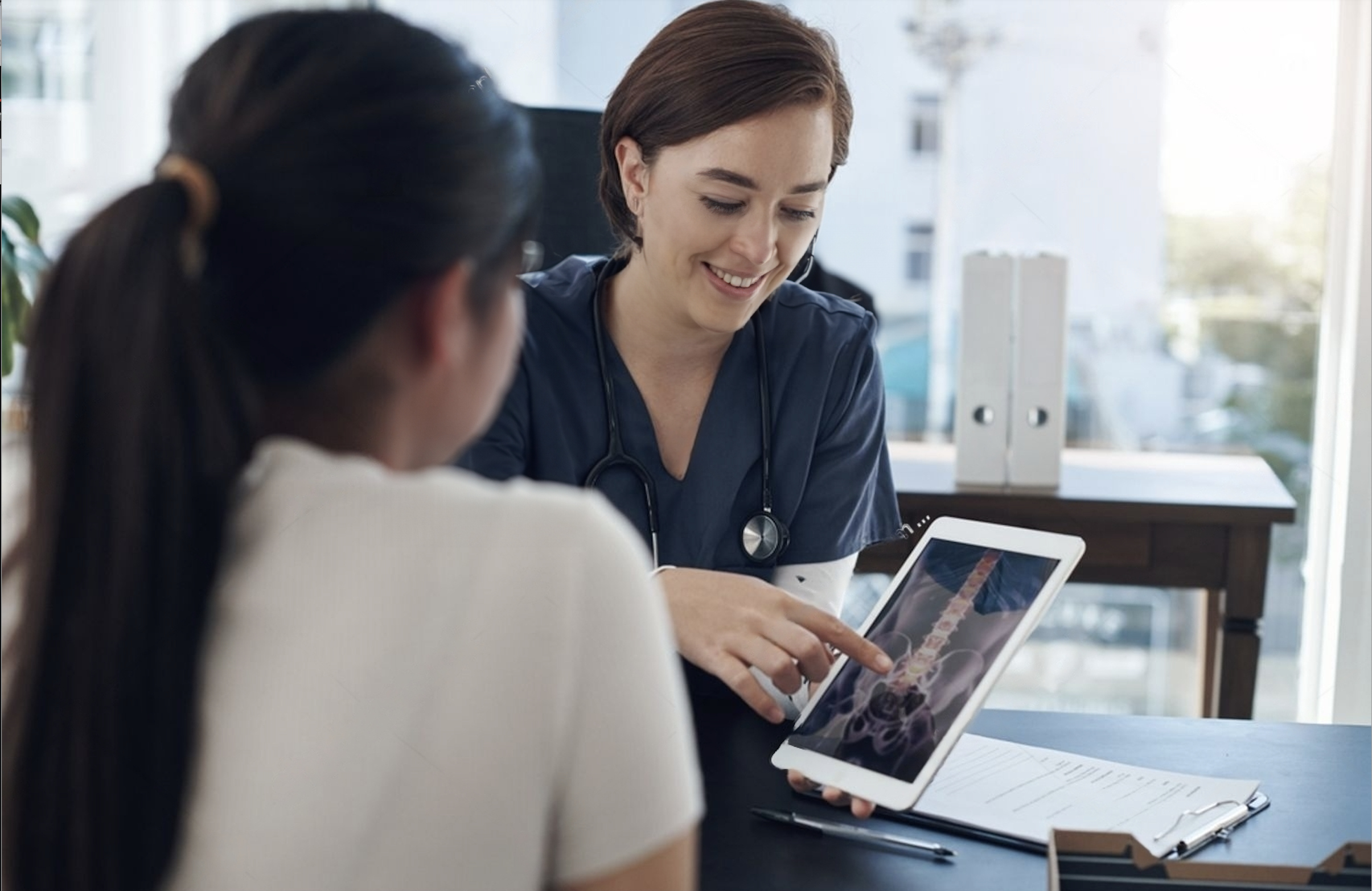 Beneficios generales Paciente accediendo a sus imágenes médicas (columna vertebral) en una tablet junto a su doctora